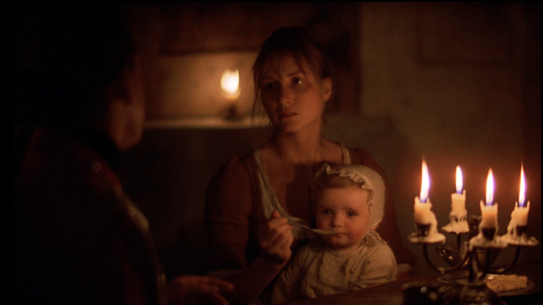 A woman feeds her baby by candlelight