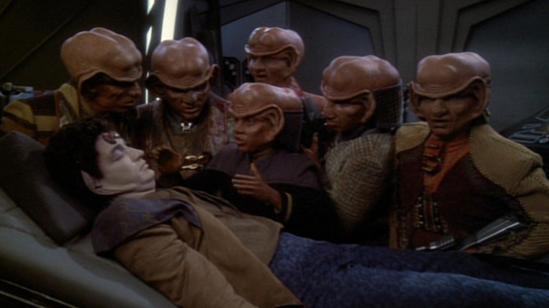 A group of Ferengi gathered around an ailing Vorta on Star Trek: Deep Space Nine