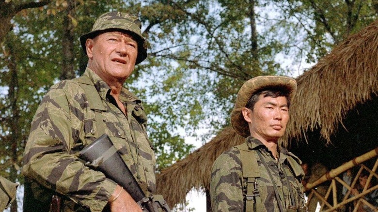 Colonel Kirby, a soldier, and Captain Nghiem standing by a barbed wire fence in The Green Berets.