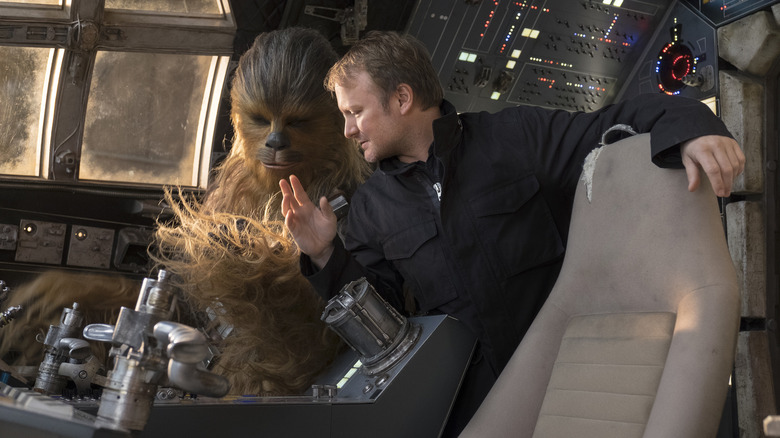 Director Rian Johnson with actor Joonas Suotamo as Chewbacca sitting in the cockpit of the Millennium Falcon in a behind-the-scenes still from Star Wars: The Last Jedi