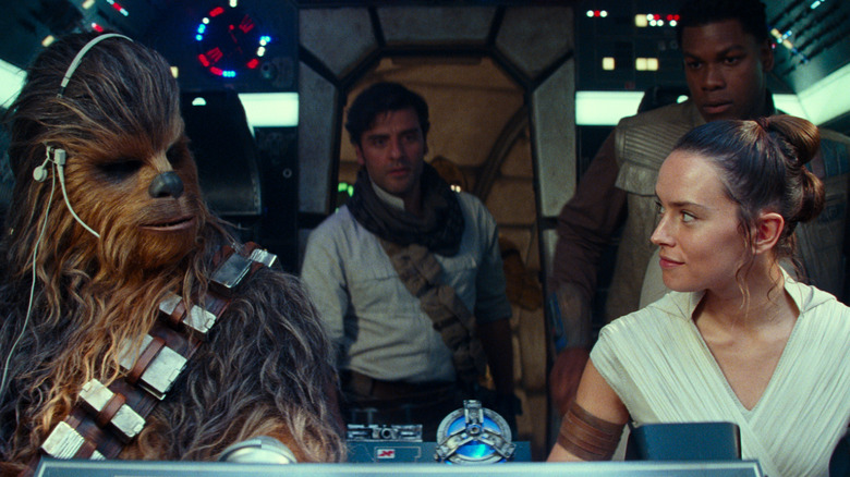 Joonas Suotamo as Chewbacca, Oscar Isaac as Poe Dameron, John Boyega as Finn, and Daisy Ridley as Rey seated in the cockpit of the Millennium Falcon in Star Wars: The Rise of Skywalker