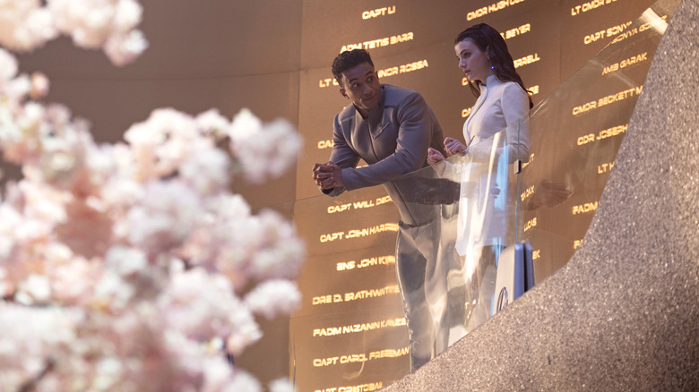 Sandro Rosta dans le rôle de Caleb Mir appuyé sur une balustrade à côté de Zoë Steiner dans le rôle de Tarima Sadal dans Star Trek : Starfleet Academy