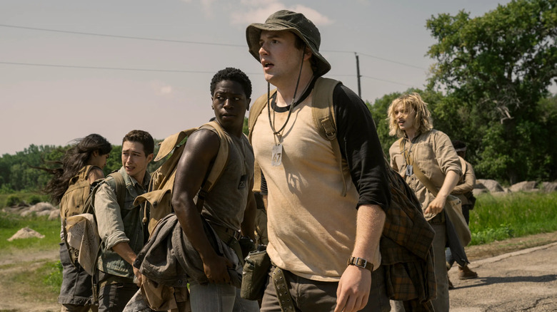 The Long Walk contestants stand on the road and watch someone die in The Long Walk