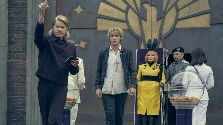 Plutach directing footage with Haymitch and Drusilla behind him in The Hunger Games: Sunrise on the Reaping