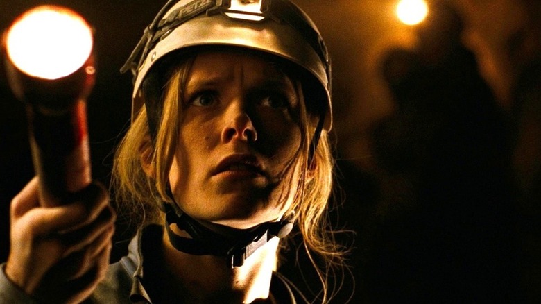 Shauna Macdonald as Sarah shines a flashlight into the darkness of a cave into "The Descent"