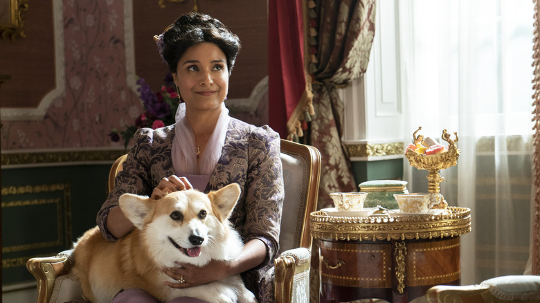 ब्रिजरटन सीझन 2 मध्ये शेली कॉन मेरी शर्माच्या भूमिकेत बसून तिच्या कुत्र्याला पेटवत आहे