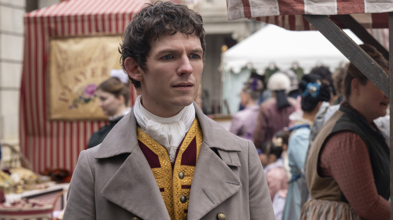 David Moorst as Alfie standing in a row of shops in Bridgerton season 4