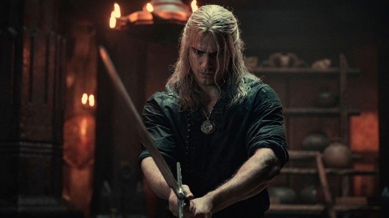 Geralt (Henry Cavill) looks downcast as he holds out his sword in The Witcher