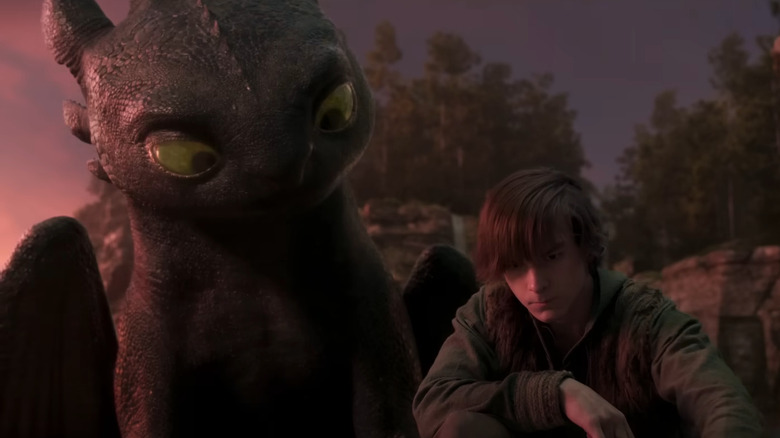 Hiccup (Mason Thames) draws in the sand as Hiccup looks on in How to Train Your Dragon (2025)