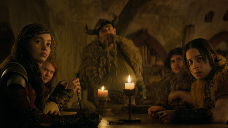 Nico Parker as Astrid, Bronwyn James as Ruffnut, Nick Frost as Gobber, Julian Dennison as Fishlegs, and Gabriel Howell as Snotlout gathered around a table in How To Train Your Dragon