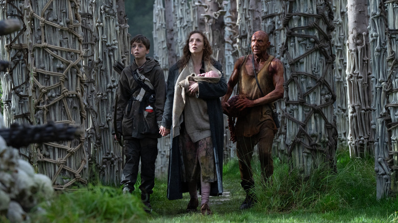 Spike (Alfie Williams), Isla (Jodie Comer), and Dr. Kelson (Ralph Fiennes) standing amid a temple made of bones in 28 Years Later