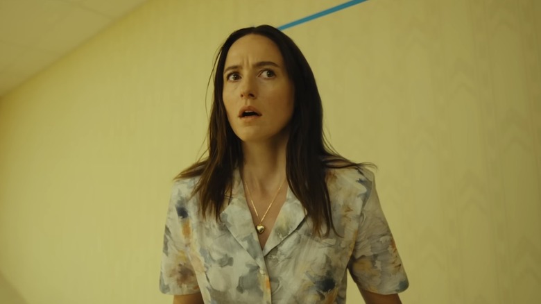 Renate Reinsve as Mary standing by a yellow wall with blue painter's tape on it in Backrooms