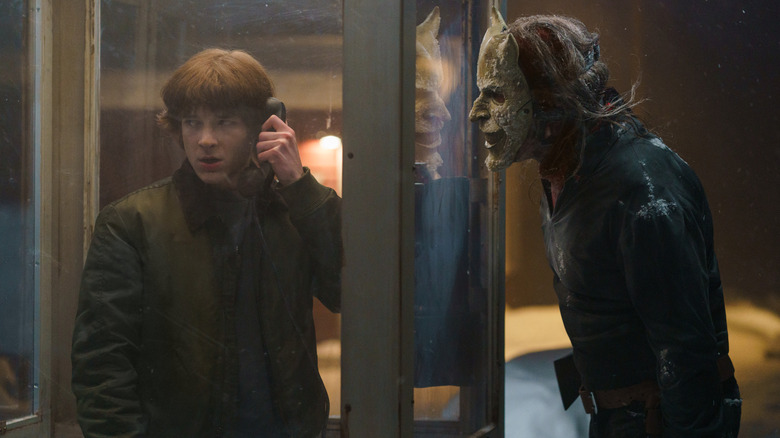 Finn standing in a phone booth with The Grabber outside in Black Phone 2