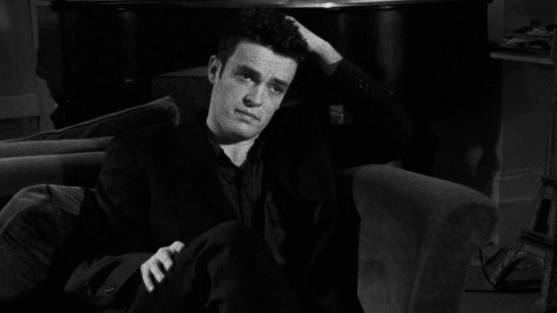 Alex Haw's Cobb sits on a couch looking across frame in Following