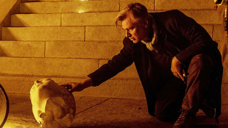 Christopher Nolan adjusting a broken-off statue head on the set of The Odyssey