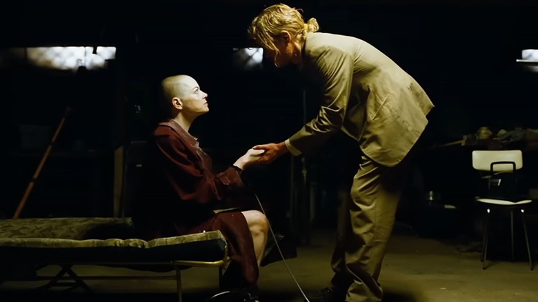 Teddy houdt Michelle bij de hand in een kelder in Bugonia