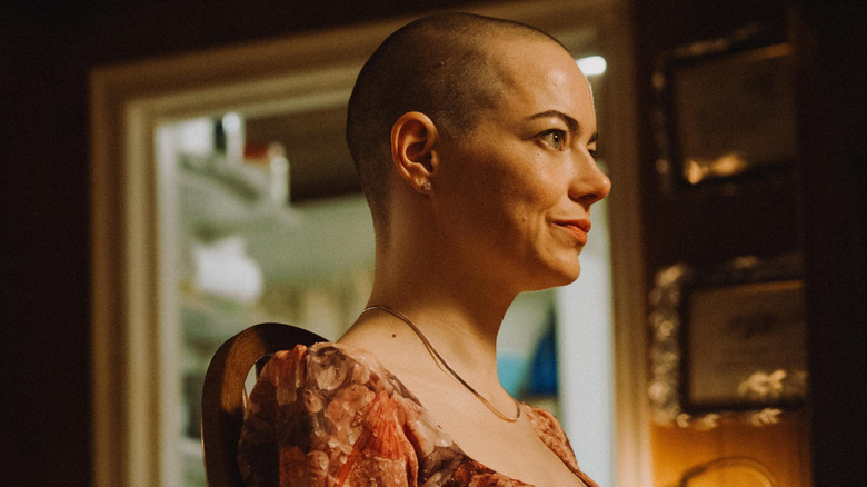 Michelle bald and wearing a pink dress in Bugonia