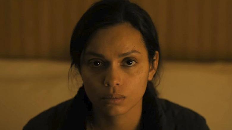 Jane Archer staring into space with a yellow light cast on her face in Psycho Killer