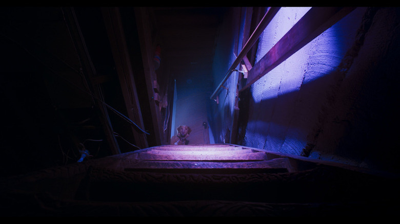 Indy sits at the foot of cellar stairs in Good Boy