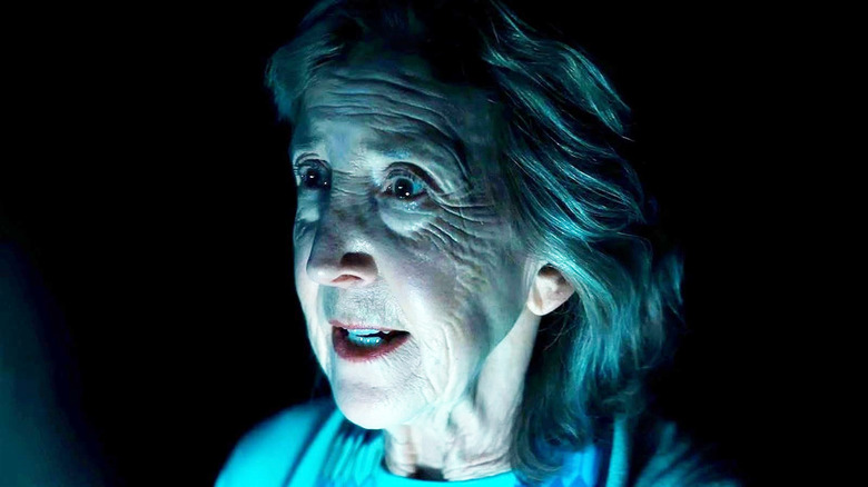 Lin Shaye as Elise Rainier with light projected beneath her in Insidious: Out of the Further