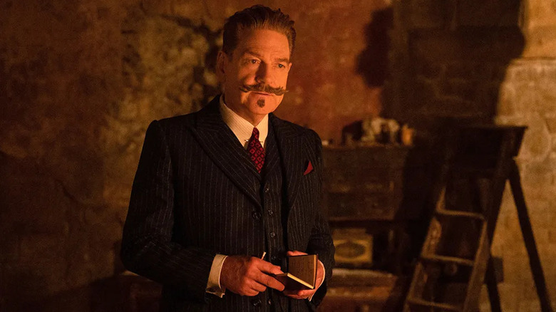 Poirot opening a notebook in a haunting in Venice
