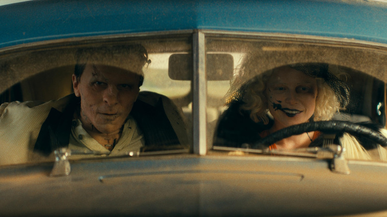 Christian Bale as Frank and Jessie Buckley as The Bride driving in a dusty car in The Bride!