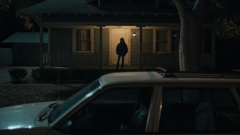 Michael Johnston as Bear sitting in his car looking at Inde Navarrette as Nikki standing menacingly on the porch of her house in Obsession