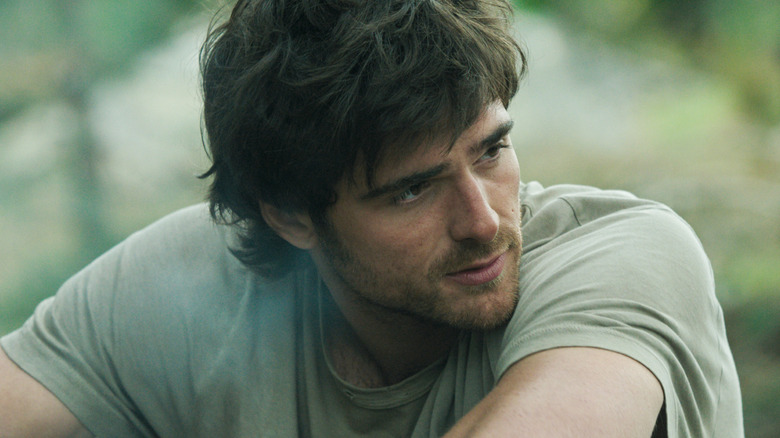 Jacob Elordi as Hig sitting down and looking over his shoulder in The Dog Stars