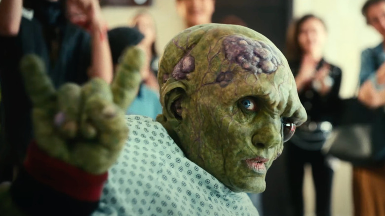 Toxie throwing horns and wearing a hospital gown in The Toxic Avenger