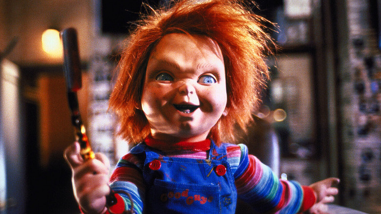 Chucky (Brad Dourif) smiles holding a bloody straight razor in Child's Play 3