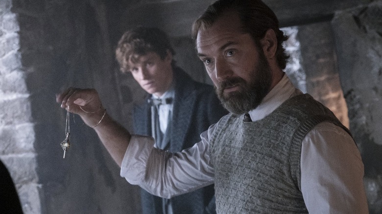 Dumbledore holding up a necklace with Newt behind him in Fantastic Beasts: The Secrets of Dumbledore