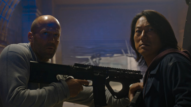 Jason Statham and Sung Kang as Shaw and Han holding each other at gun point in Fast X
