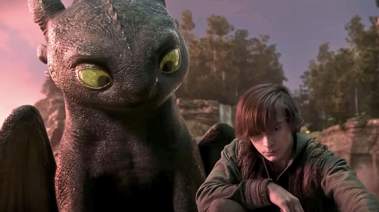 Toothless looking down quizzically at young sulking Hiccup in How to Train Your Dragon