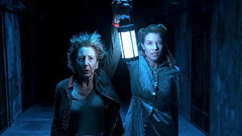 Elise and Melissa go hunting for demons, looking towards the camera in horror, in the astral plane in Insidious: The Last Key