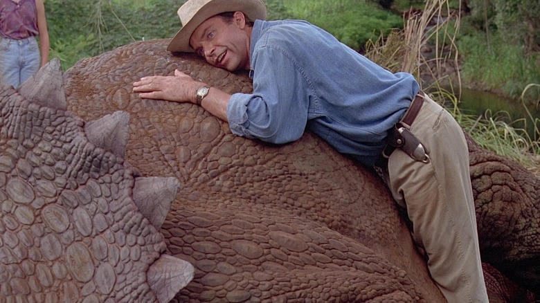 Dr, Alan Grant laying on a breathing triceratops in Jurassic Park