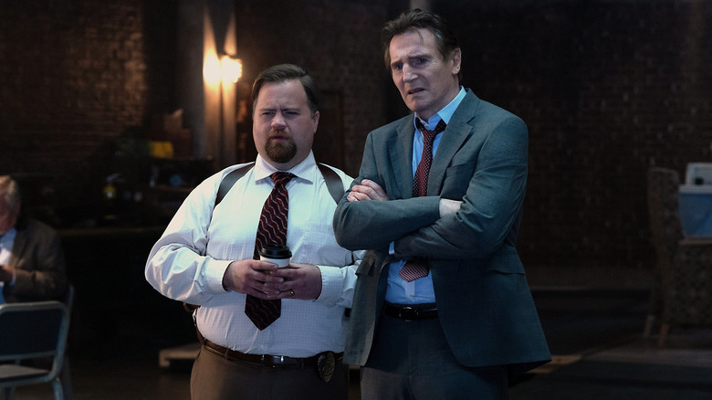 Paul Walter Hauser as Ed Hocken Jr. standing next to Liam Neeson as Frank Drebin Jr. looking confused in The Naked Gun (2025)