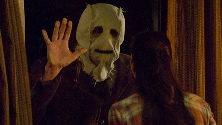 Scarecrow with his hand on a window in The Strangers: Chapter 1