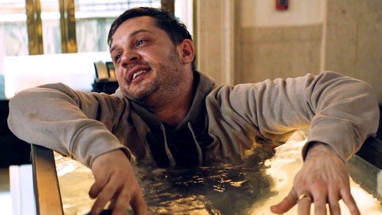 Eddie Brock smiles like a fool while in a lobster tank in Venom