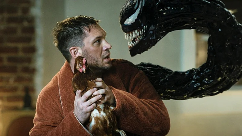 Eddie looks scared holding a chicken while talking to Venom in Venom: Let There Be Carnage