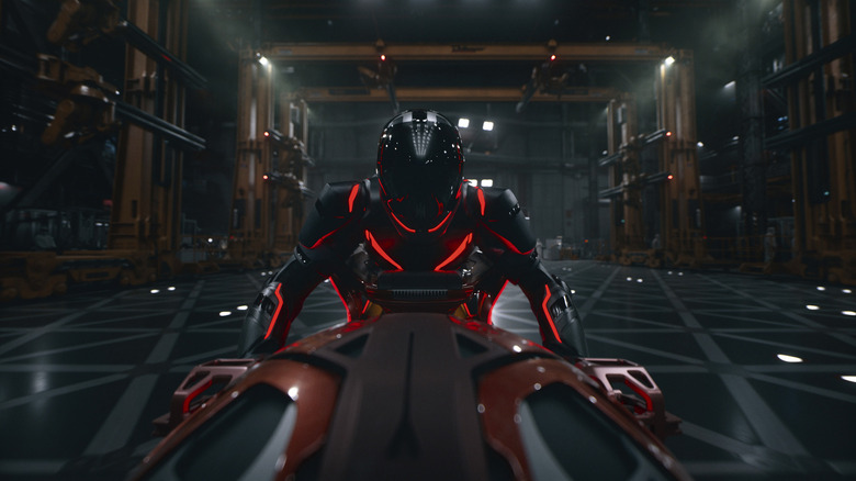 A person in a Tron suit wearing a helmet and riding a motor vehicle