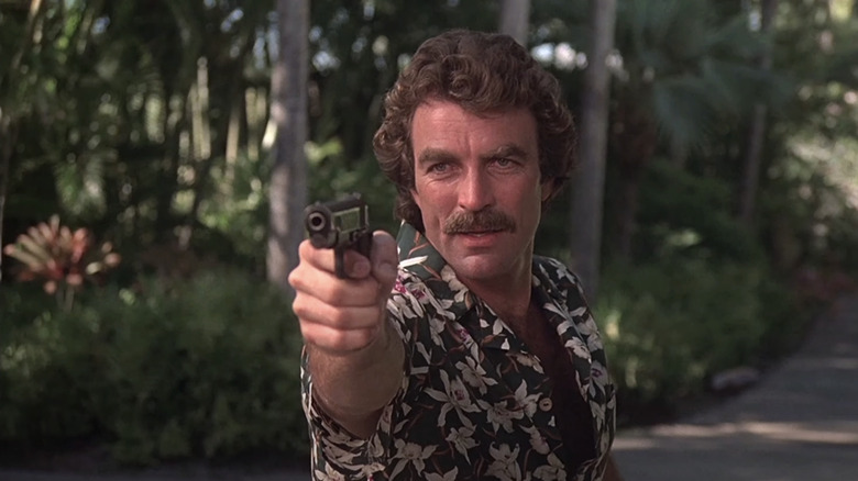 Tom Selleck as Thomas Magnum points his pistol in Magnum, P.I.