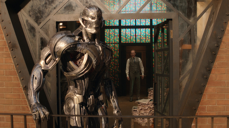 James Spader as the voice of Ultron standing on a balcony in front of Paul Bettany as Vision in VisionQuest