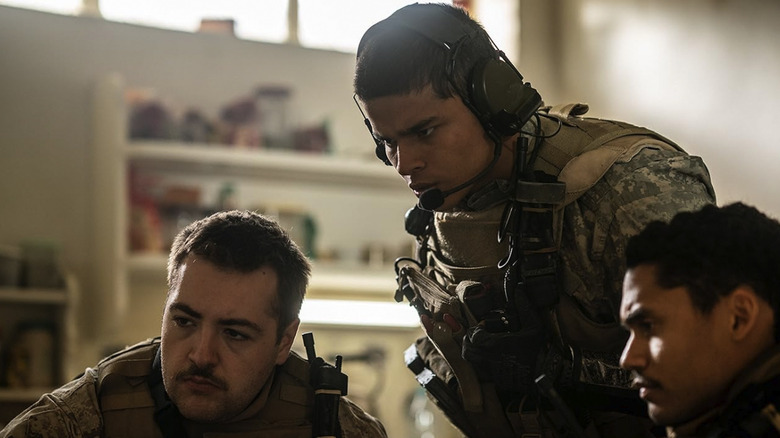 D'Pharaoh Woon-A-Tai wears a headset and looks down at something off screen in Warfare