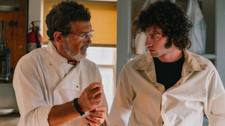 Antonio Banderas as Chef José Vatel standing next to Dominic Sessa as Anthony Bourdain in a kitchen in Tony