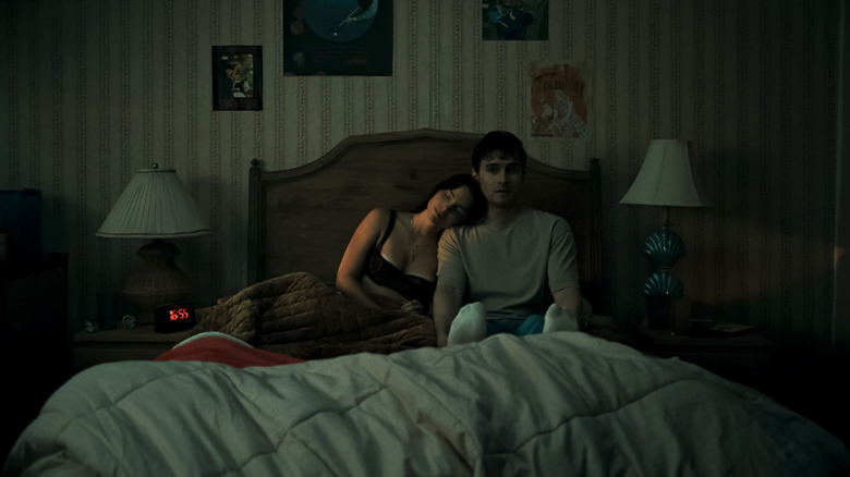 Michael Johnston as Bear sitting uneasily in bed next to Inde Navarrette as Nikki resting her head on his shoulder in Obsession