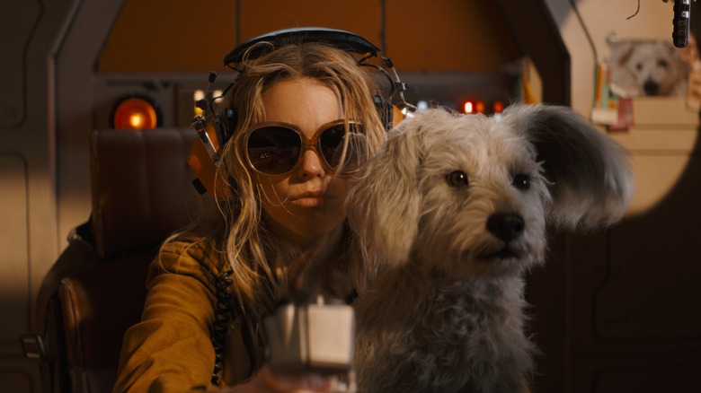 Kara listening to music while Krypto looks enthusiastically out the window in Supergirl