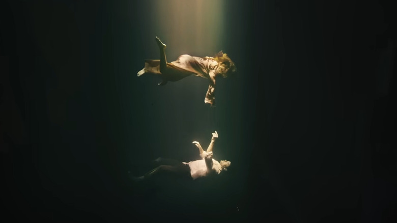 Mae floating above Nicholas Bannister in a big case of water in Reminiscence