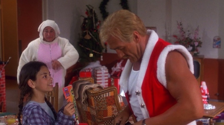 A little girl offering Blake, aka Santa, a present in Santa with Muscles