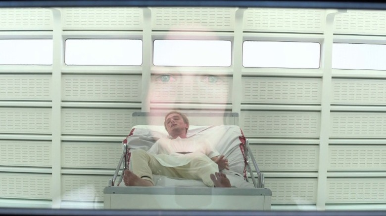 Katniss watches as a brainwashed Peeta writhes in his bed