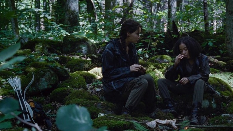 Katniss and Rue sitting in the woods and eating